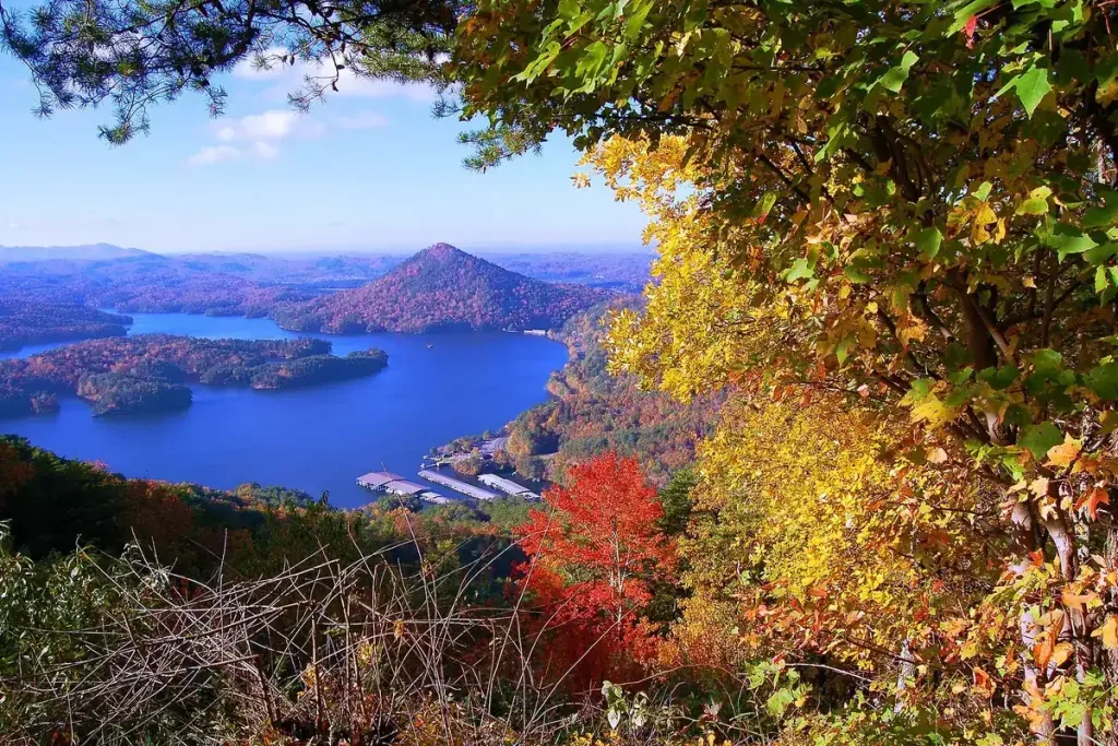 Red and gold leaves frame a blue lake and forested peaks in Cherokee National Forest, Tennessee