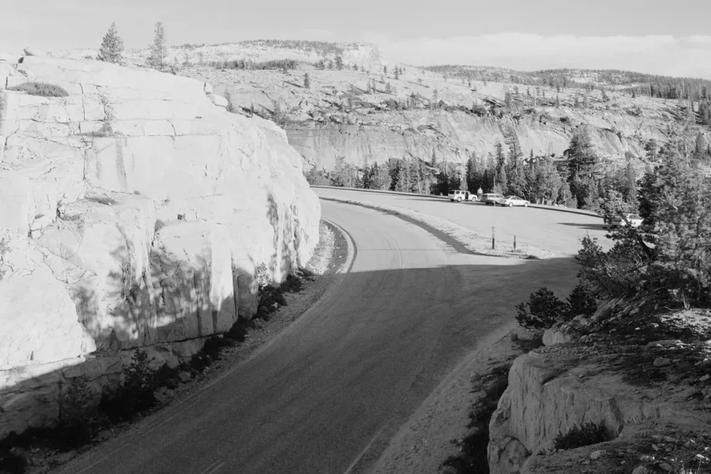Black-and-white view of Tioga Road curving past a granite road cut near Olmsted Point in Yosemite National Park, California